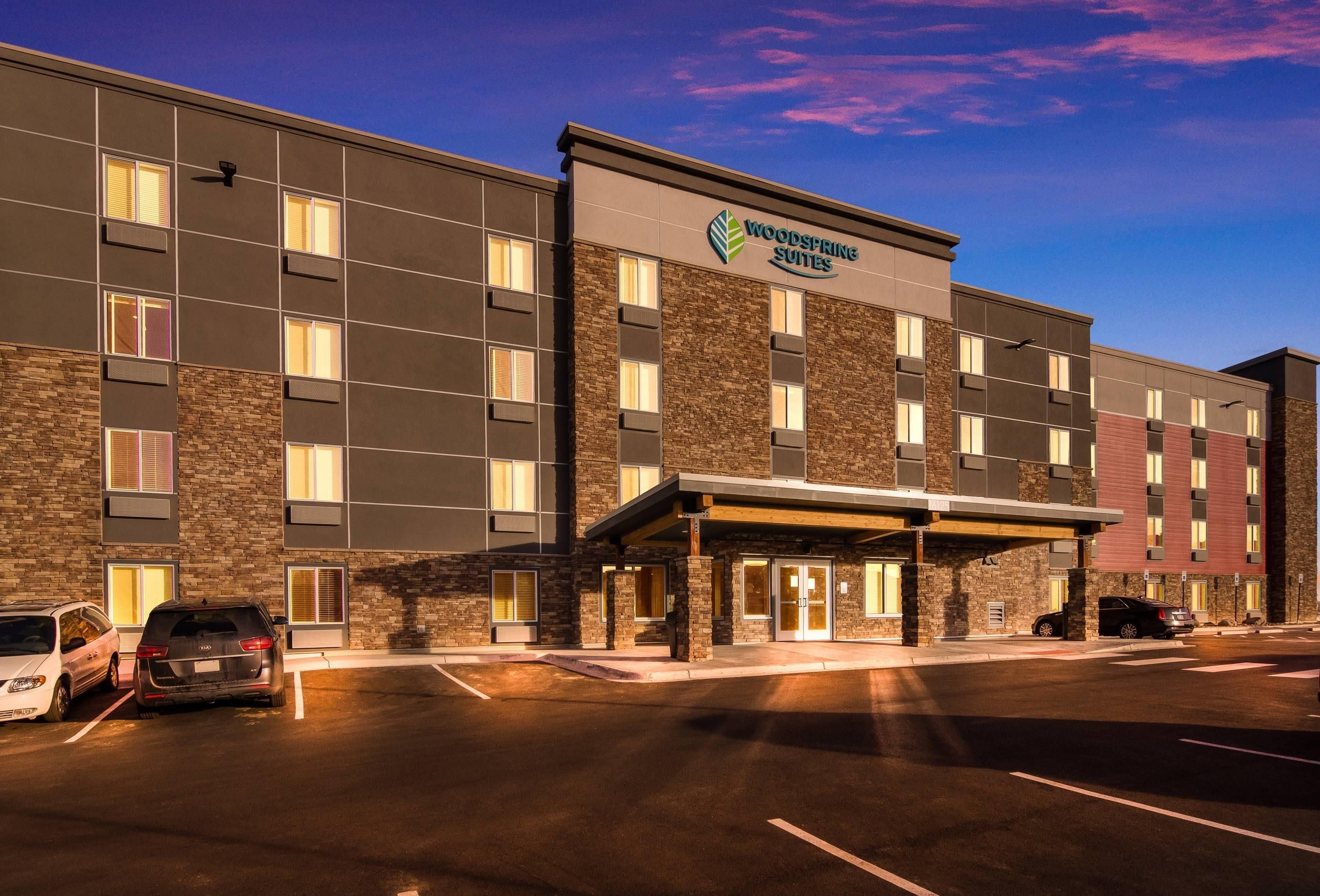 Un hôtel à plusieurs étages au design moderne, avec une enseigne bien visible indiquant « Woodspring Suites ».