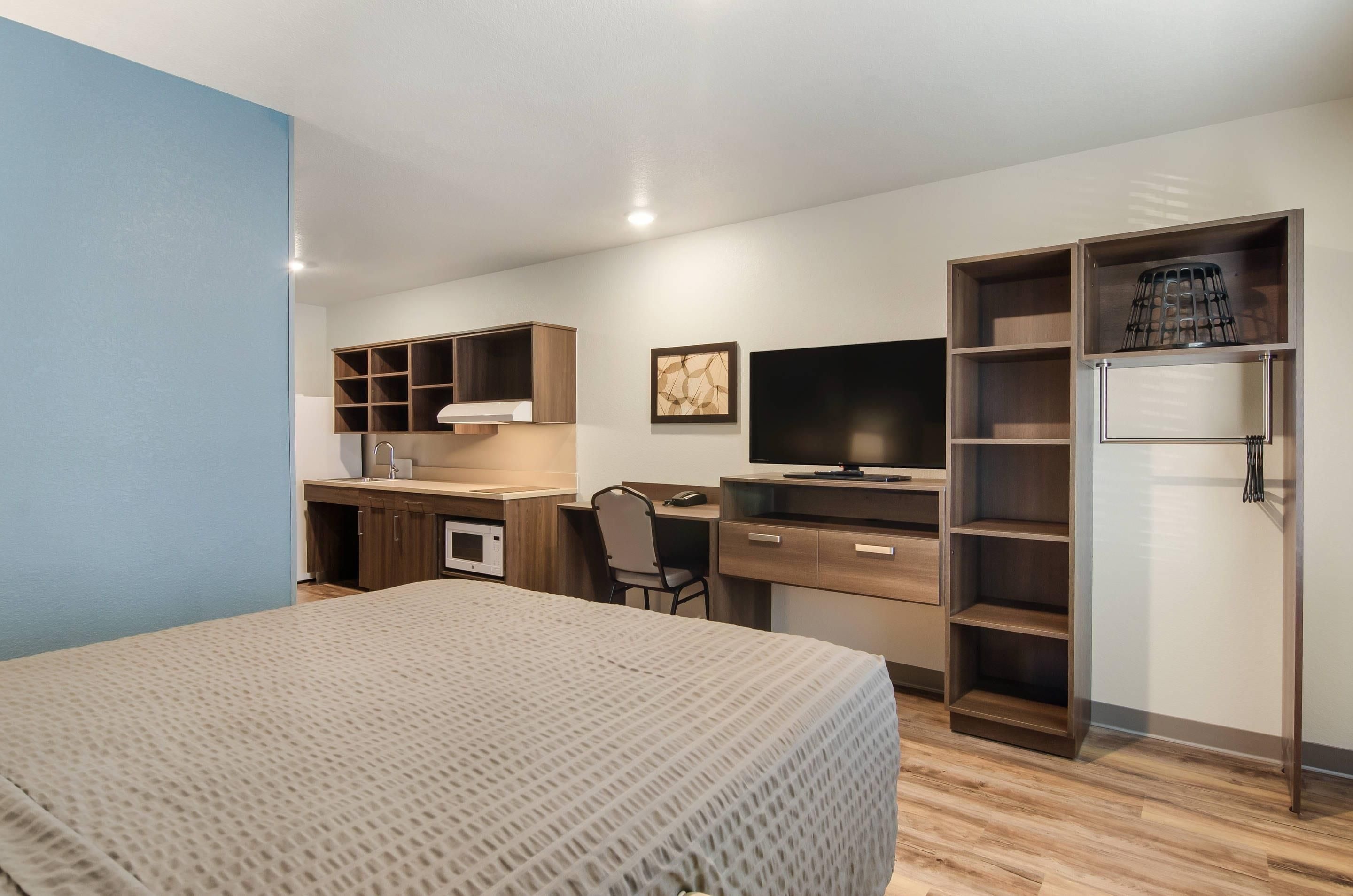 Habitación de hotel compacta con cama, escritorio, silla, televisión y armario.