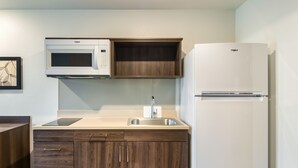 A kitchen with a microwave, sink, and refrigerator. - WoodSpring Suites Thornton-North Denver (Thornton)