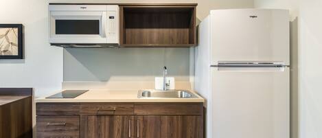 A kitchen with a microwave, sink, and refrigerator.