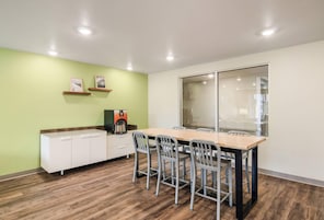 Una cocina moderna con una mesa y sillas de madera, una cafetera y un ventanal con vistas.