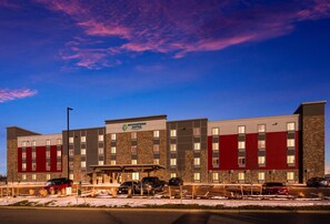 A multi-story hotel with a stone facade and a red accent wall. - WoodSpring Suites Thornton-North Denver (Thornton)