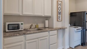 A kitchen with white cabinets, a microwave, a sink, a stove, and a refrigerator. - University Suite "C" (Marion)