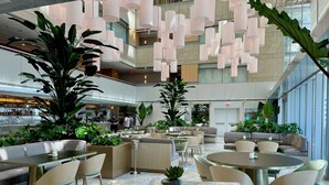 Un hall d’entrée spacieux avec de nombreux espaces de détente, un bar et de grandes plantes.