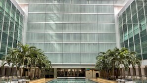 Une vaste piscine intérieure dotée d’une architecture moderne, entourée d ’espaces de détente et de palmiers.