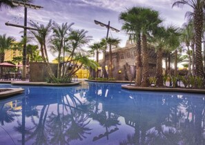 Relax by the serene pool surrounded by lush landscaping and a rustic building.