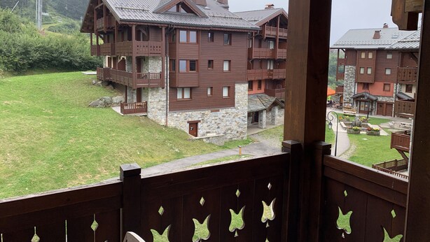 A multi-story wooden building with balconies, stone foundations, and a grassy courtyard. - D305 - 73m2 - 4P - 8/10 pers (Prapoutel)