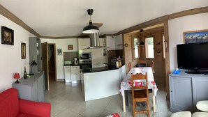 A compact living space with a kitchenette, a dining area, and a seating area with a red sofa and a television. - D305 - 73m2 - 4P - 8/10 pers (Prapoutel)