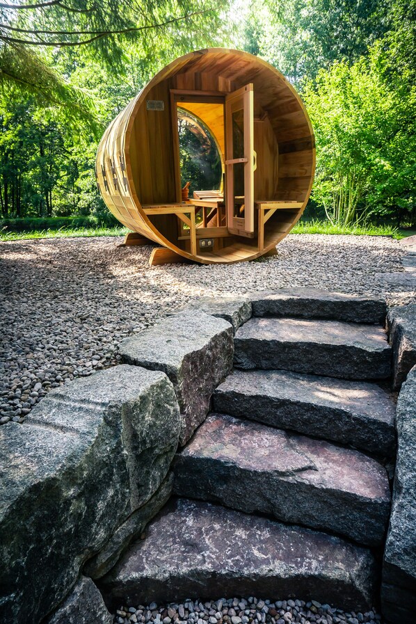 A wooden cabin with a circular design, a staircase leading up to it, and a forested background.