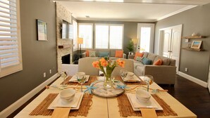 Ein Essbereich mit Tisch für vier Personen, einem Kamin und einem Wohnzimmer mit Sofa und Kissen.