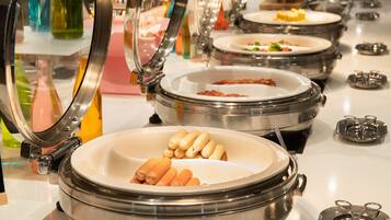 A buffet setup with multiple serving stations, each with a covered dish and utensils.
