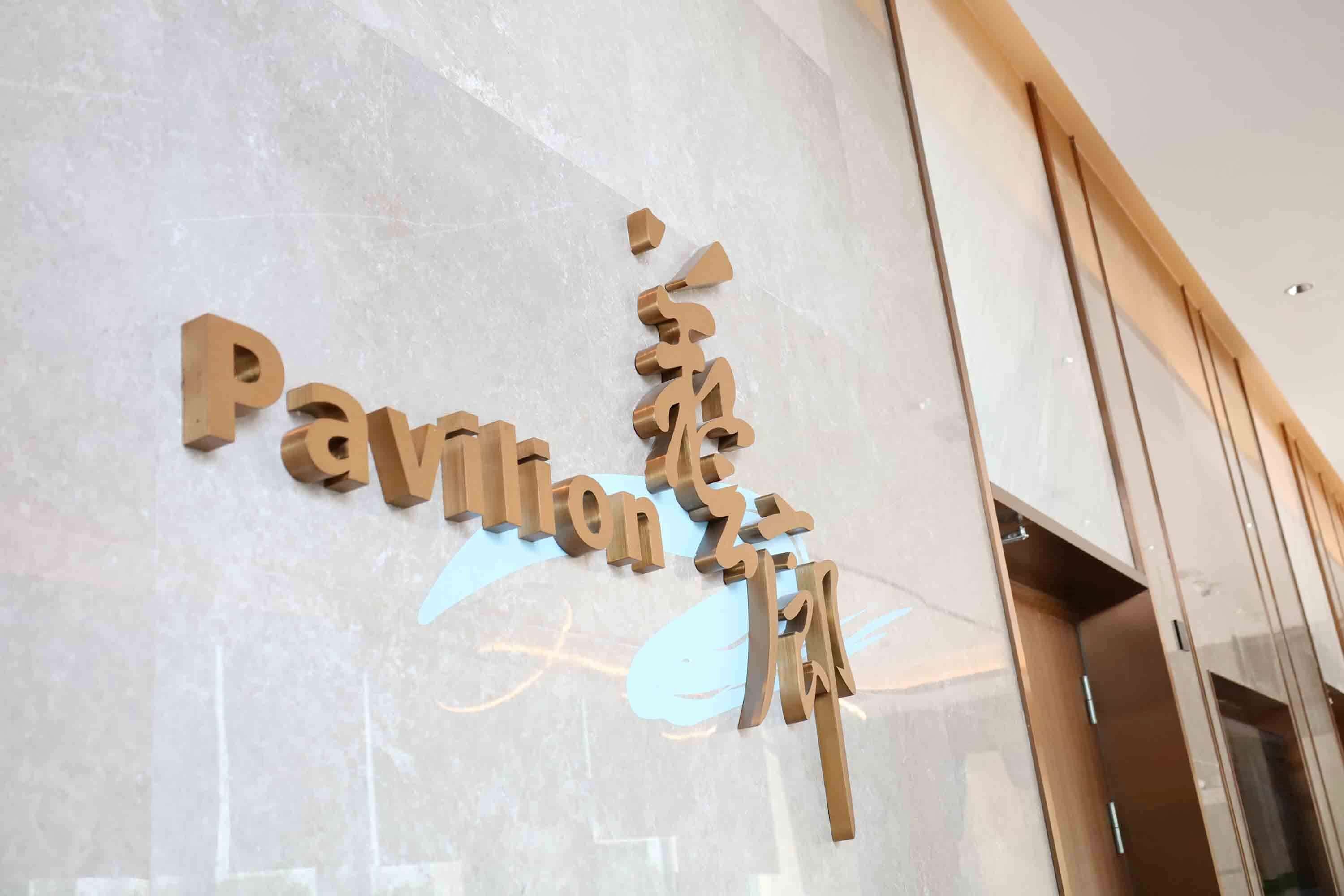 A sign with the name "Pavilion Hotel" in a modern font on a reflective surface.