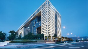 Un edificio moderno de gran altura con un diseño de esquina llamativo, que cuenta con ventanas amplias y fachada de vidrio.