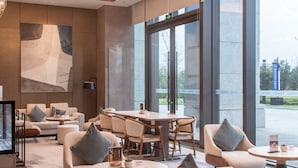 Un moderno vestíbulo de hotel con una amplia zona de estar, grandes ventanales e iluminación contemporánea.