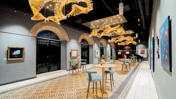 An interior with a patterned floor, tables with chairs, and hanging light fixtures.