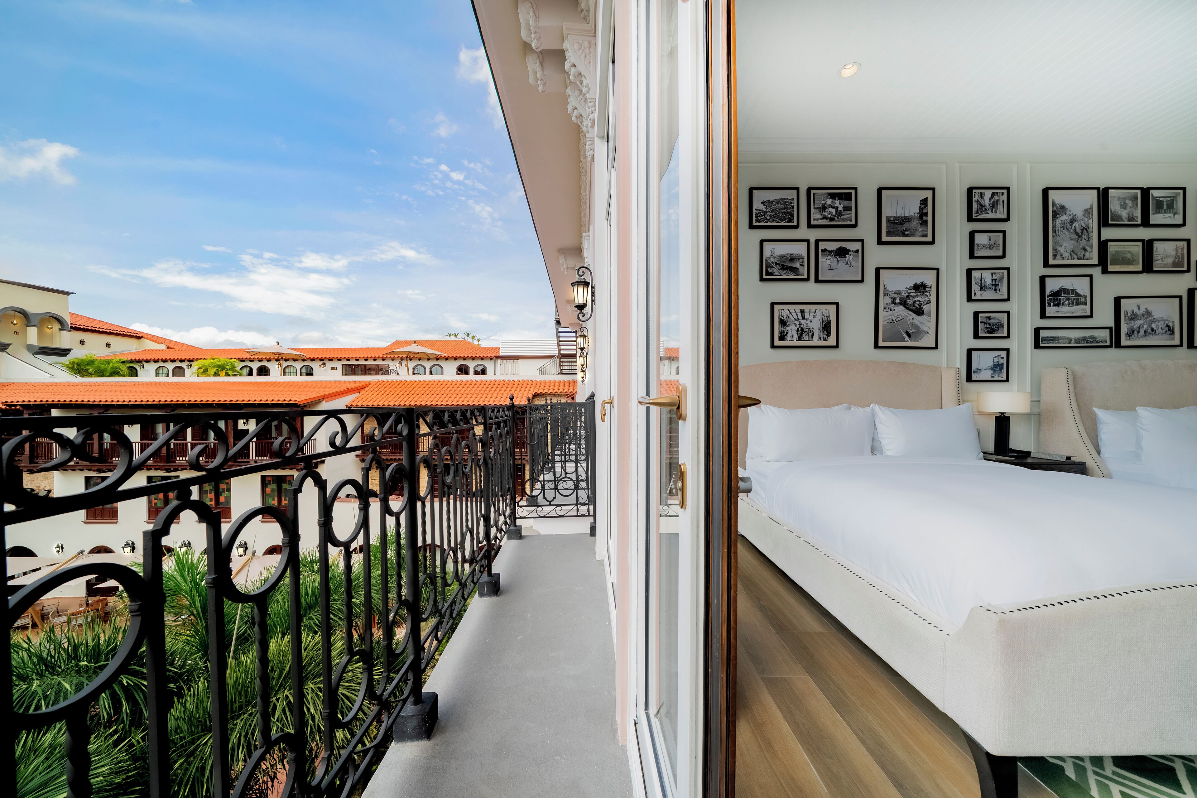 A hotel room with a balcony, a bed, and a wall with framed pictures.