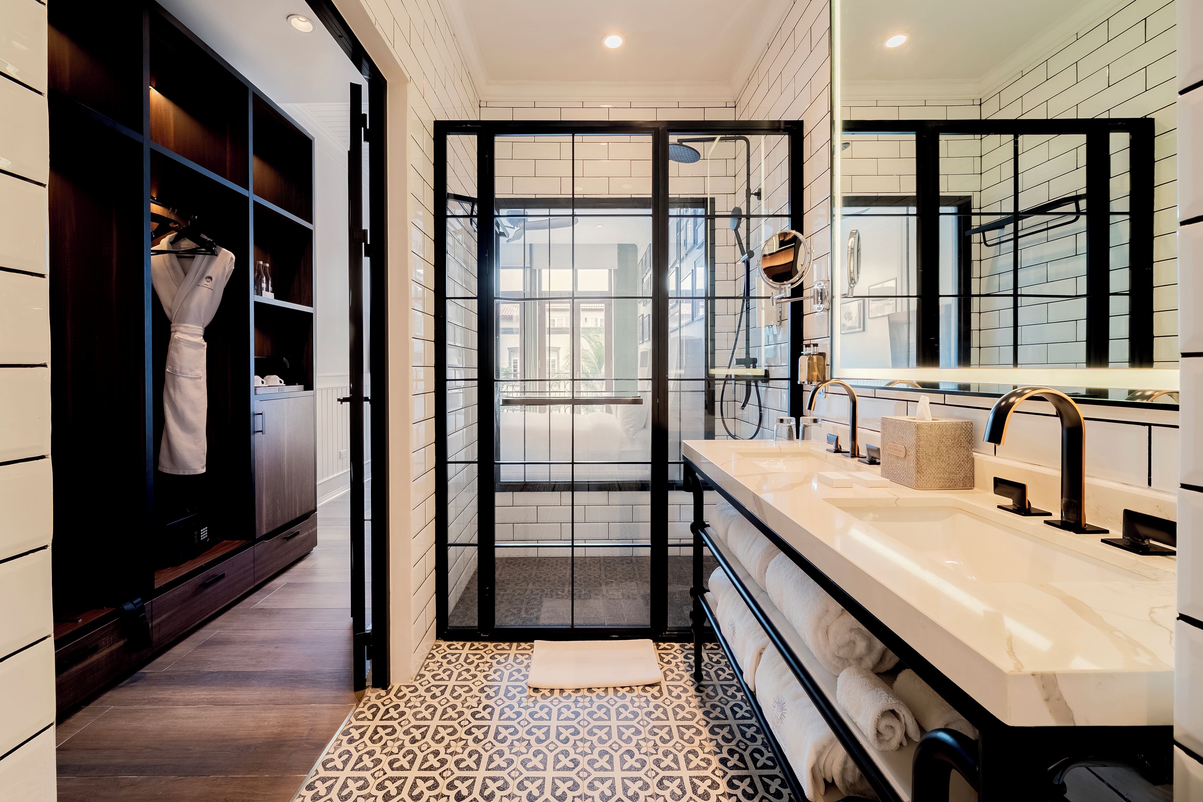 A modern bathroom with a walk-in shower, a vanity with a large mirror, and a patterned floor.