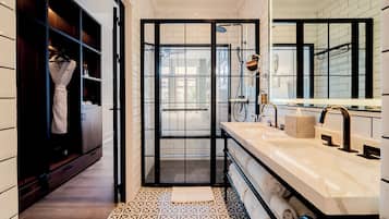 Un baño moderno con cabina de ducha, tocador con un espejo grande y suelo estampado.