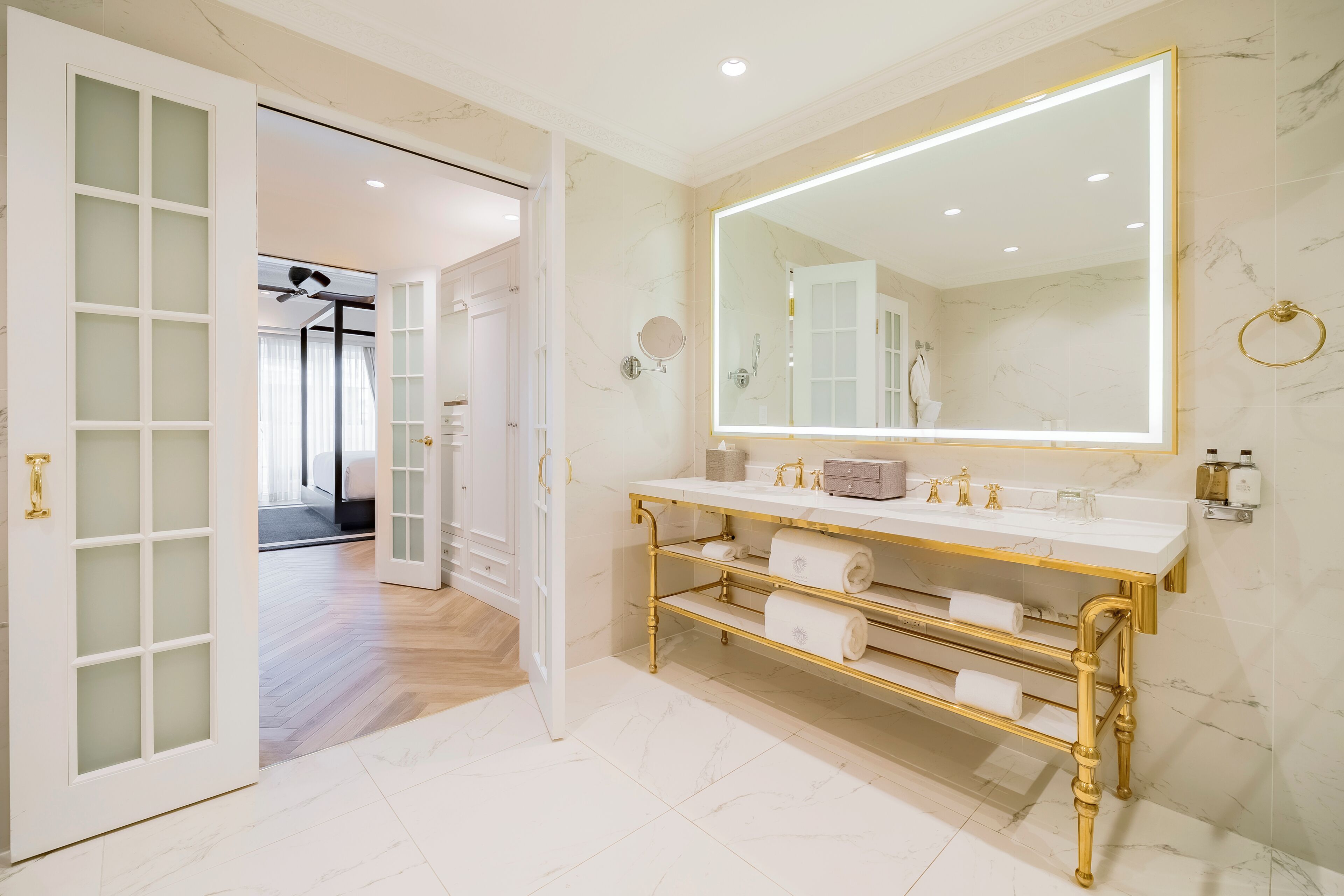 Un baño con un espejo grande, un tocador con detalles dorados y un dispensador de papel higiénico.