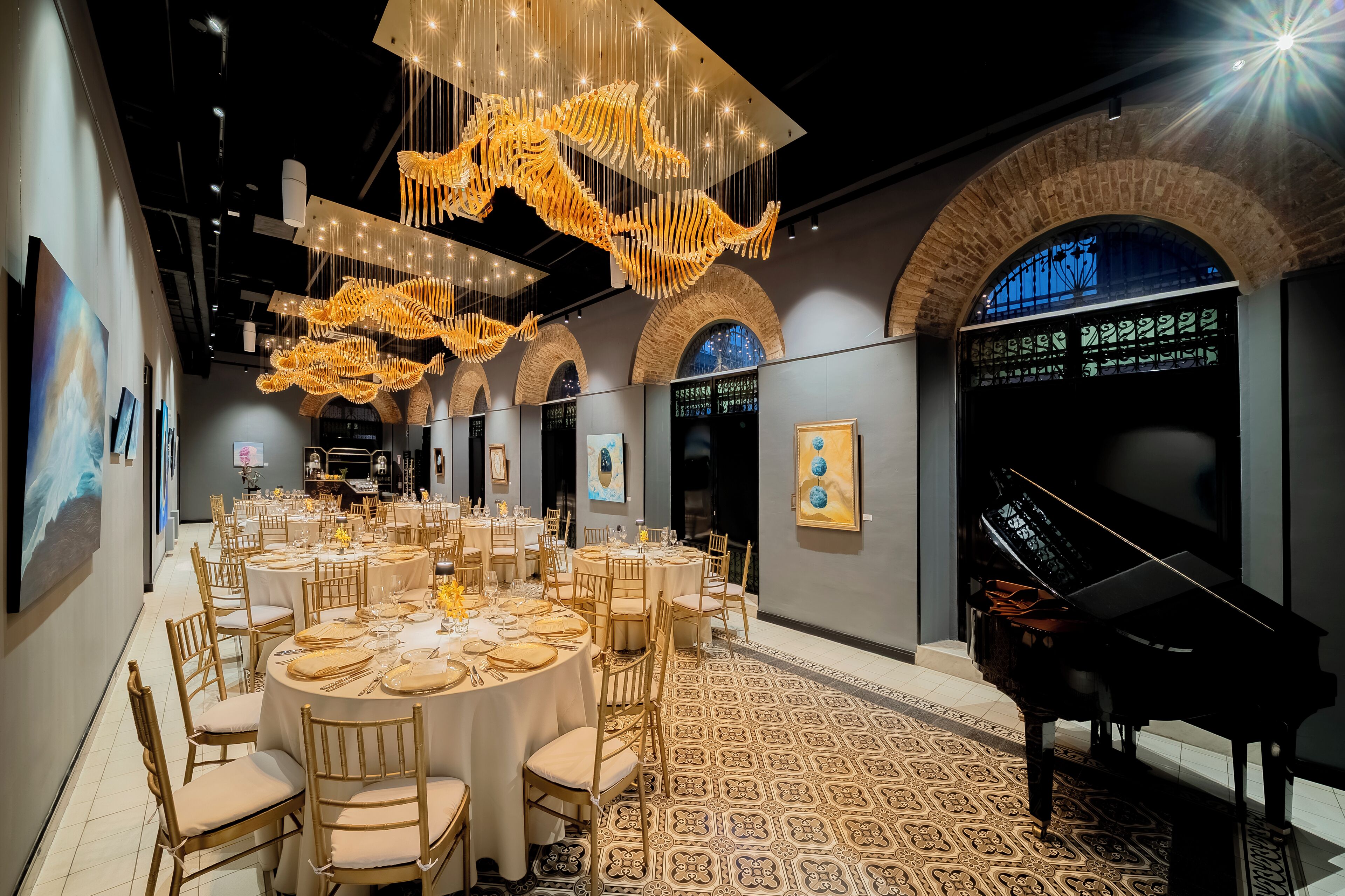 Un salón de banquetes con mesas redondas, candelabros y un piano de cola.