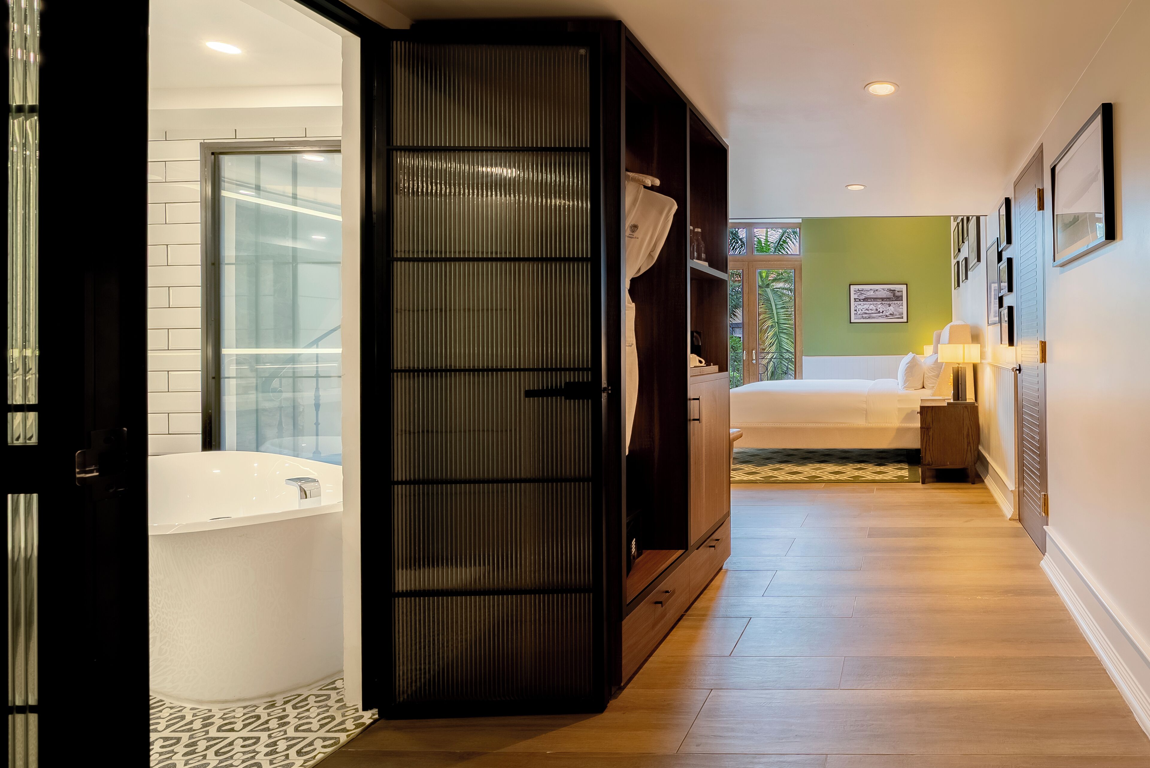 Une salle de bain moderne avec une grande baignoire, une armoire en bois et un lit en arrière-plan.