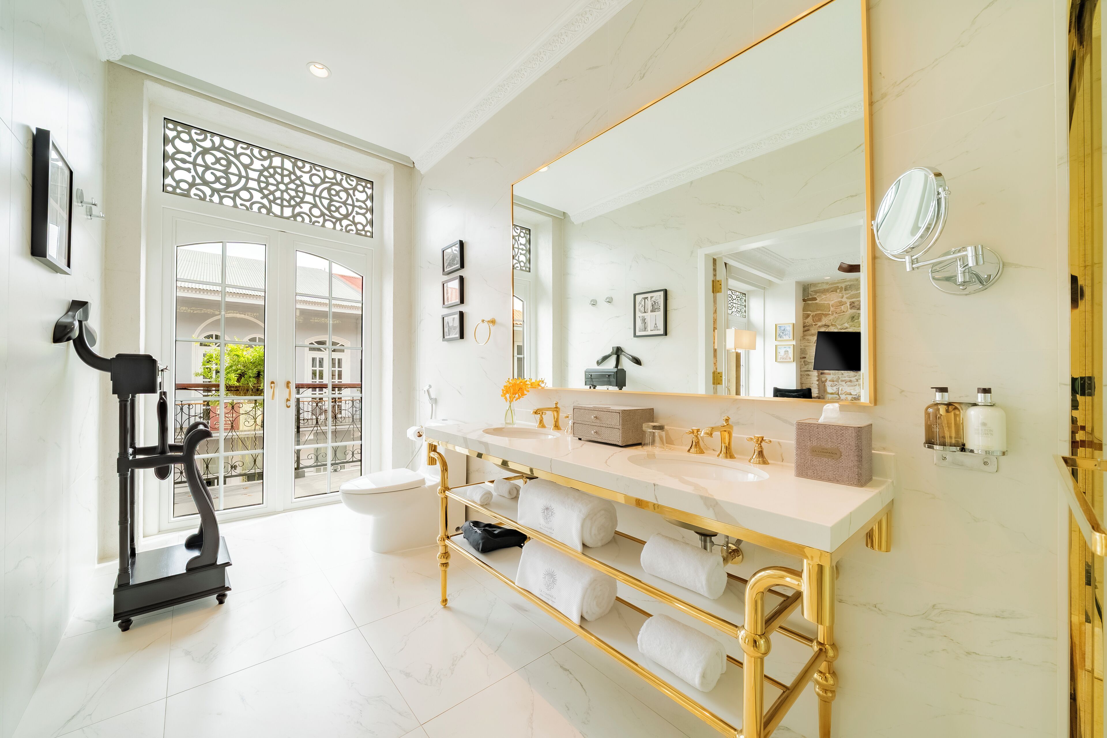 A luxurious bathroom with a large mirror, gold fixtures, and a vanity with multiple sinks.