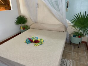 Relax in a cozy space with a neatly made bed, decorative towels, and a beautiful flower arrangement.
