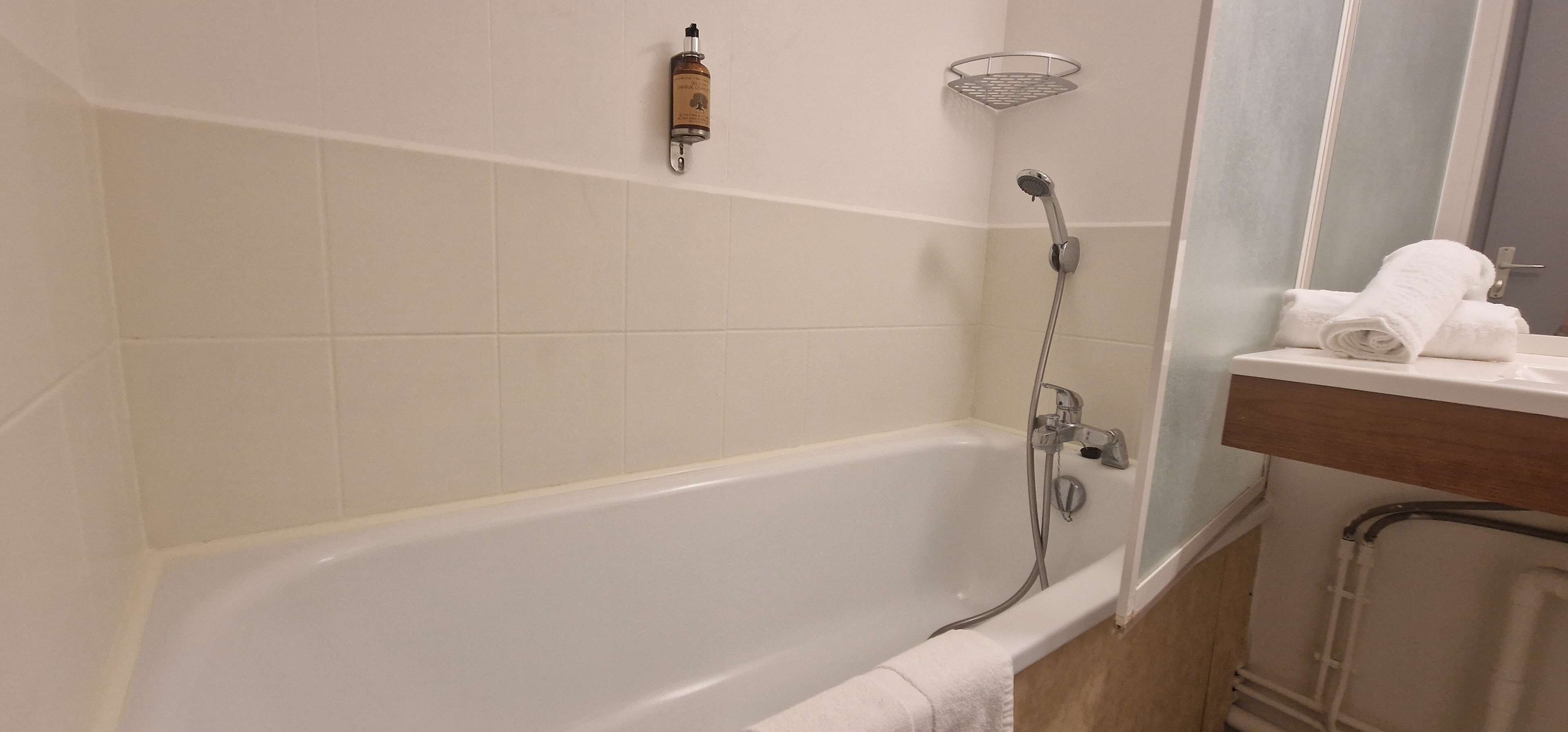 Un baño con una bañera blanca, una ducha y un perchero para toallas.
