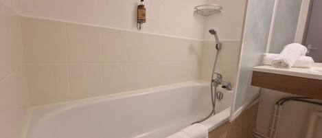 Un baño con una bañera blanca, una ducha y un perchero para toallas.