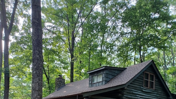 A rustic log cabin with a porch, surrounded by trees and a gravel driveway. - 
Your Mountain Cabin Getaway Awaits! (Wintergreen)