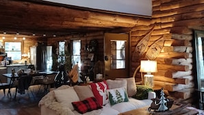 A cozy log cabin interior with a wooden dining area, a sofa with decorative pillows, and a rustic wooden chest. - 
Your Mountain Cabin Getaway Awaits! (Wintergreen)