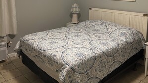 A bedroom with a bed, a ceiling fan, a nightstand, a lamp, a painting, and a sign on the wall. - Right on the beach with a GREAT VIEW of the Atlantic Ocean!  Shore Drive, APATB1 (myrtle beach)