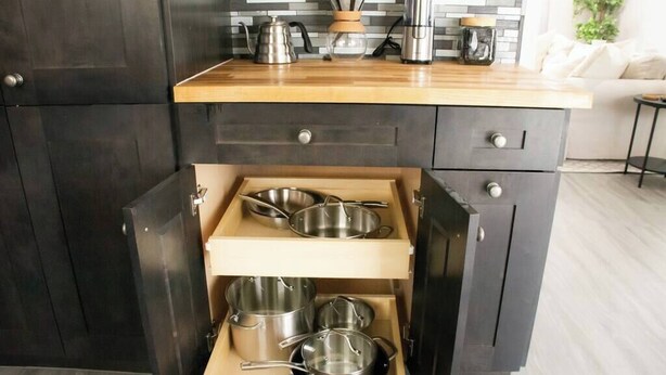 A kitchen with dark cabinetry, a wooden countertop, and a built-in utensil holder with pots and pans.