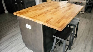 A kitchen with a wooden island, dark cabinets, and a grey floor.