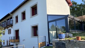 Et moderne hus med flere vinduer, en balkon og en stenvæg med en plantekasse.
