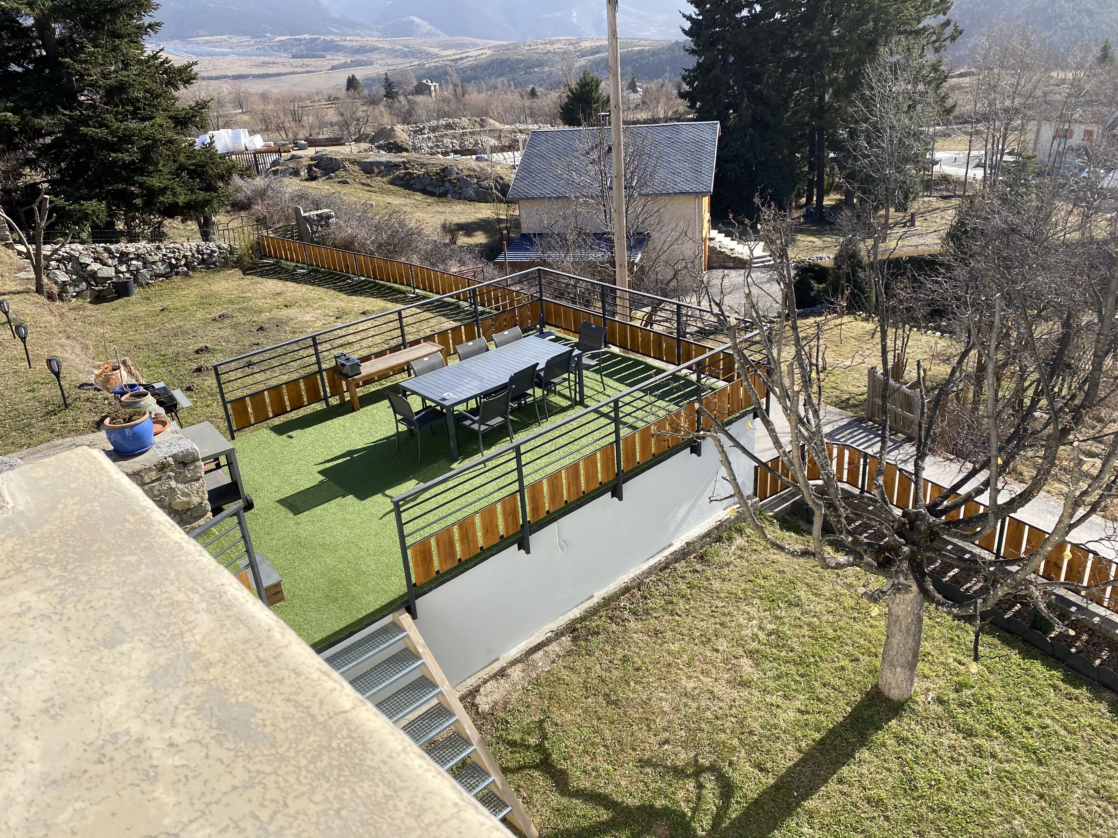 A rooftop terrace with a dining area, a small garden, and a view of the surrounding landscape.