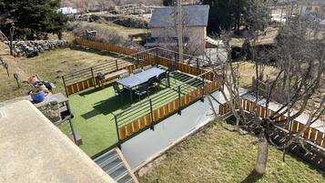 A rooftop terrace with a dining area, a small garden, and a view of the surrounding landscape.