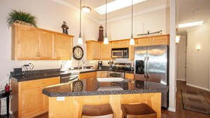 A modern kitchen with wooden cabinets, granite countertops, stainless steel appliances, and pendant lighting. - Promo! Top Floor, Corner Oceanfront Condo - Indoor Pool/Hot Tub/Wifi and HDTV! (Depoe Bay)