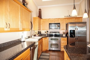Enjoy cooking in this well-equipped kitchen with a granite countertop, stainless steel appliances, and wooden cabinets.