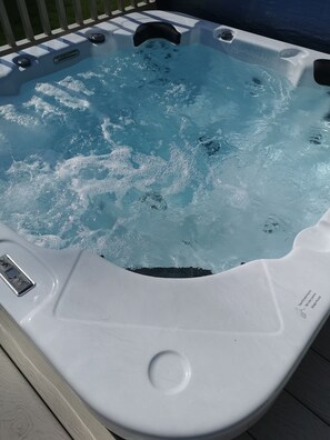 Un bain à remous doté d’un panneau de commande et d’une étiquette indiquant les consignes de sécurité.