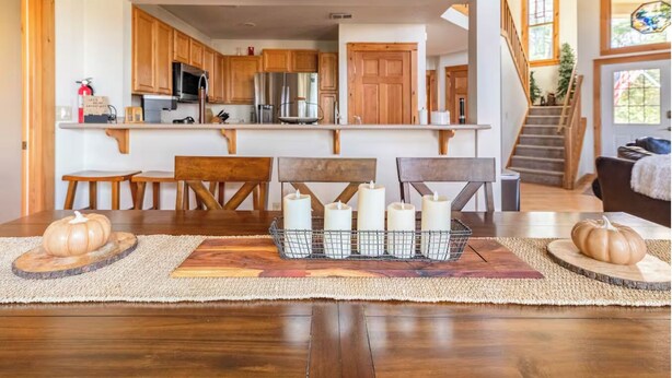 Un comedor con mesa de madera, sillas y un centro de mesa con velas.