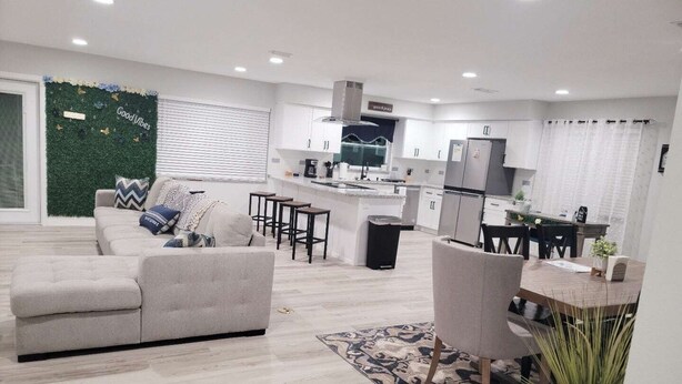 Una cocina moderna con armarios blancos, una isla central y un comedor con mesa y sillas.