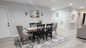 Un comedor con una mesa y sillas de madera, un tapete estampado y decoración en la pared.