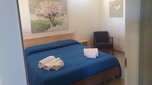 Une chambre à coucher avec un lit, une chaise et un tableau accroché au mur.