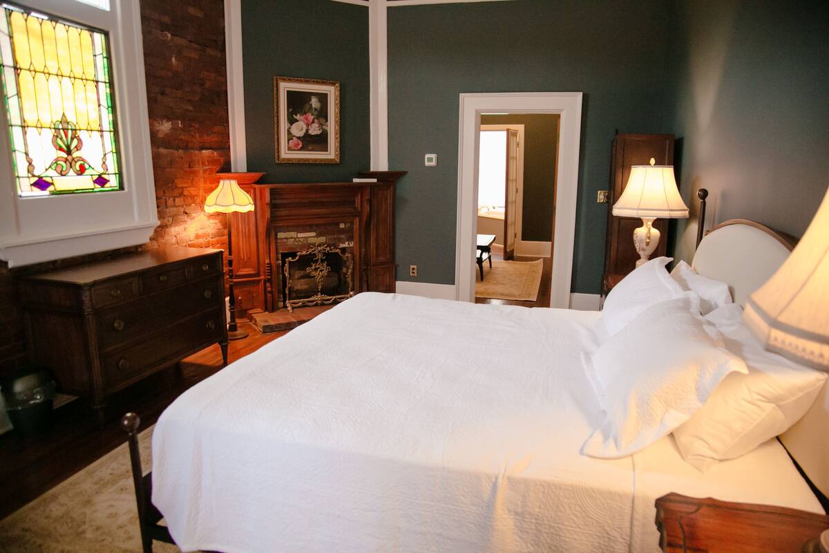Une chambre à coucher avec un lit, une commode et une cheminée.