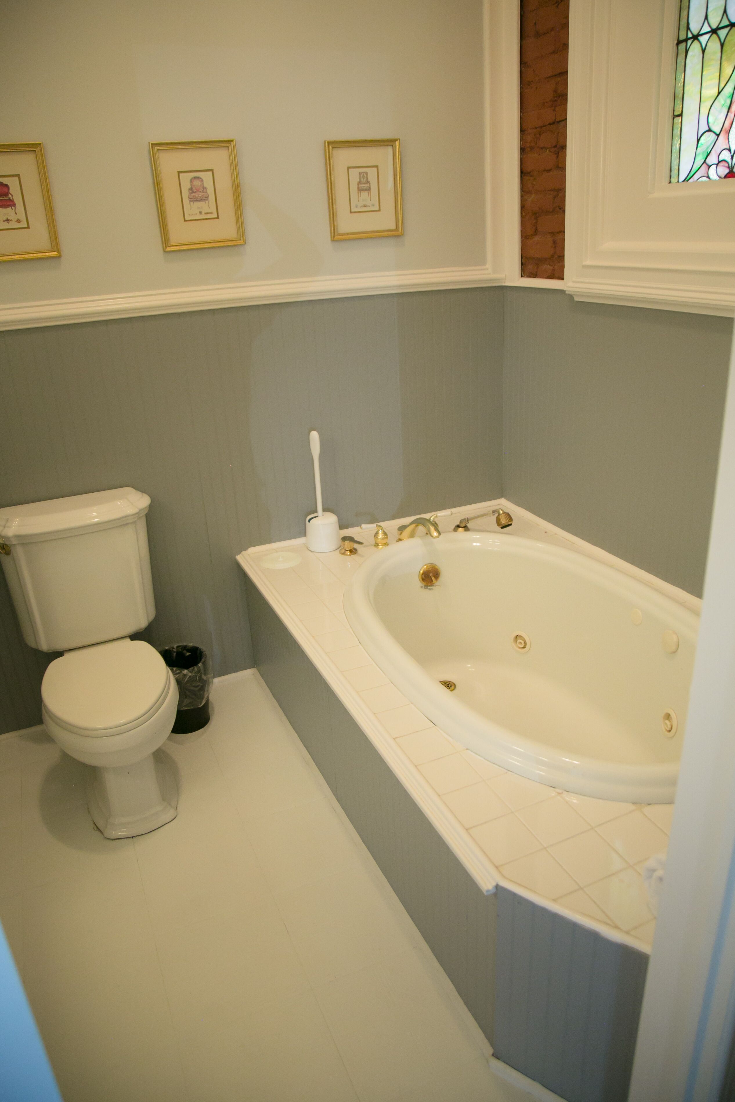 A bathroom with a toilet, a bathtub, and a small trash bin.