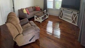 A living room with a sofa, a coffee table, a TV on a stand, and a ceiling fan. - Relax on Lake- cozy, spacious, and stylish (Ponca City)