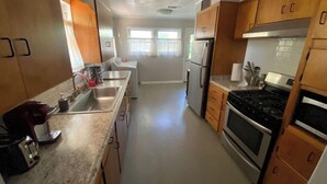 A modern kitchen with stainless steel appliances, wooden cabinets, and a granite countertop. - Relax on Lake- cozy, spacious, and stylish (Ponca City)