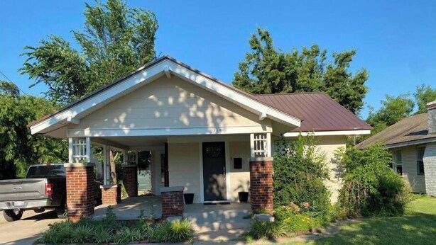 A single-story house with a front porch, a brick chimney, and a garage. - Relax on Lake- cozy, spacious, and stylish (Ponca City)