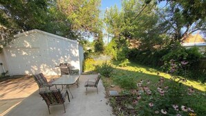 A covered patio with a table and chairs, a grill, and a small shed. - Relax on Lake- cozy, spacious, and stylish (Ponca City)